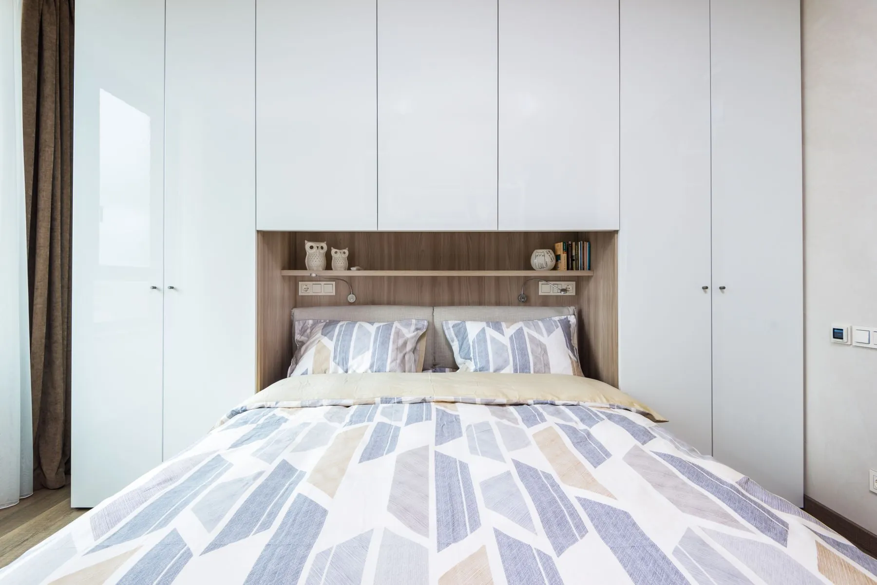 Quarto com roupeiro branco à volta da cama